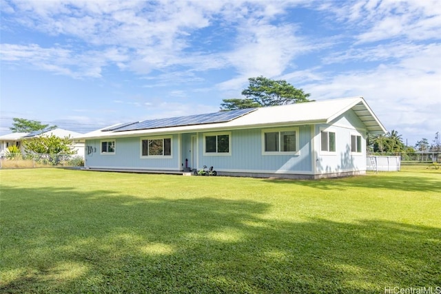 back of house with a yard and solar panels