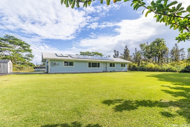 rear view of property with a yard and solar panels