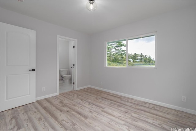 unfurnished bedroom featuring light hardwood / wood-style floors and connected bathroom