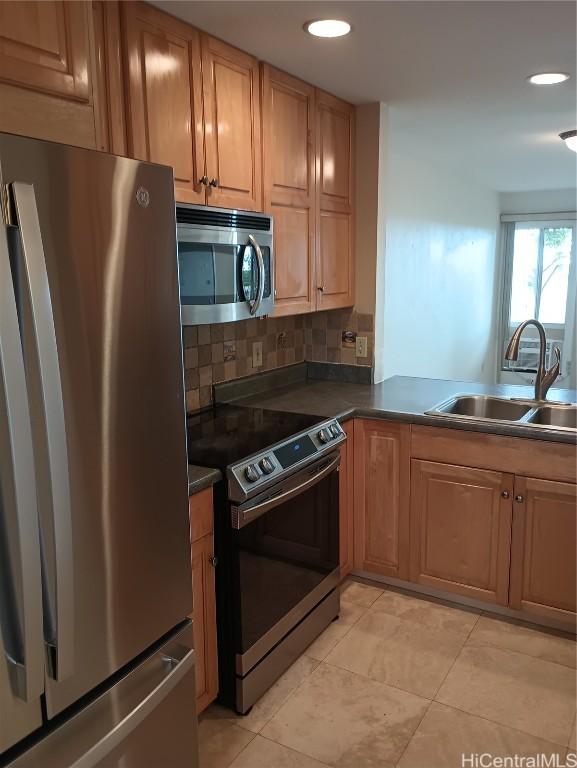 kitchen with tasteful backsplash, appliances with stainless steel finishes, sink, and light tile patterned floors