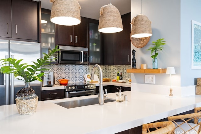 kitchen featuring dark brown cabinetry, tasteful backsplash, decorative light fixtures, a kitchen breakfast bar, and stainless steel appliances