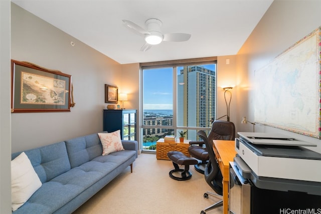 office featuring ceiling fan, a wall of windows, and light carpet