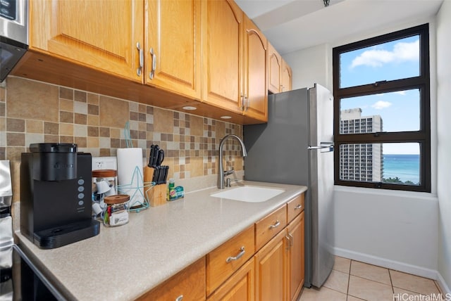 kitchen featuring sink, backsplash, light tile patterned floors, and a wealth of natural light