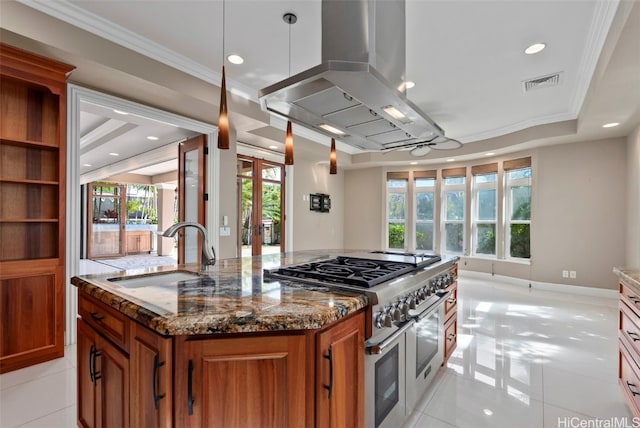 kitchen with dark stone countertops, double oven range, sink, island range hood, and a kitchen island with sink