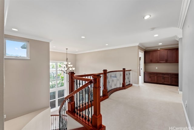 hall featuring light colored carpet, ornamental molding, and an inviting chandelier