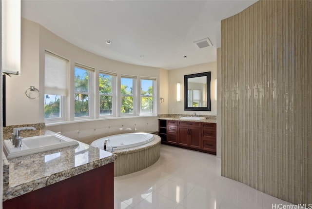 bathroom featuring tiled bath, vanity, and tile patterned flooring