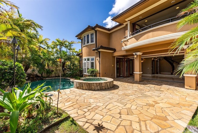 back of house featuring a patio area, a swimming pool with hot tub, and a balcony