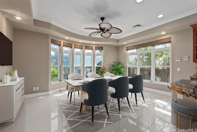 tiled dining space featuring ceiling fan, a tray ceiling, and ornamental molding