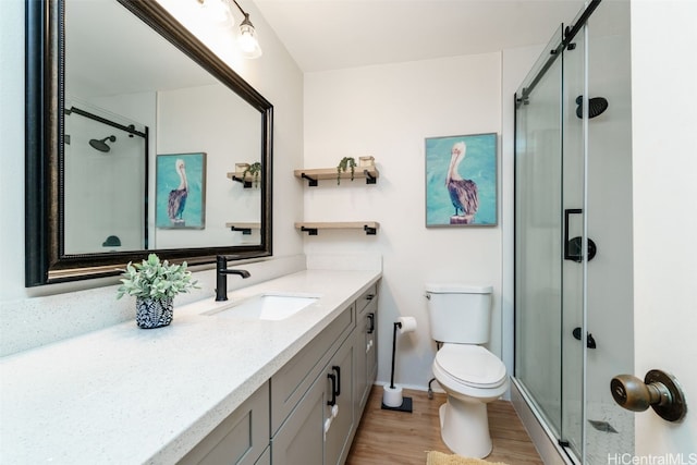 bathroom featuring hardwood / wood-style floors, toilet, vanity, and walk in shower