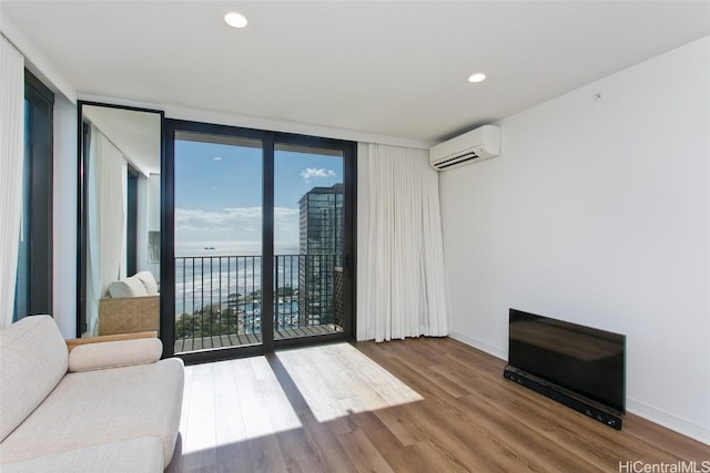 living room featuring a wall of windows, a wall mounted air conditioner, hardwood / wood-style floors, and a wealth of natural light