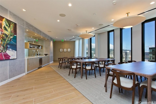 dining area featuring sink, a wall of windows, and light wood-type flooring