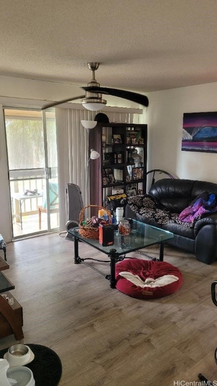 living room with ceiling fan, wood-type flooring, and a textured ceiling