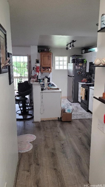 kitchen with dark hardwood / wood-style floors, stainless steel fridge, black range with electric stovetop, and a textured ceiling