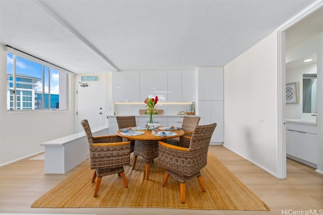 dining area featuring light wood-type flooring and a textured ceiling