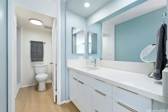 bathroom with toilet, vanity, and hardwood / wood-style flooring