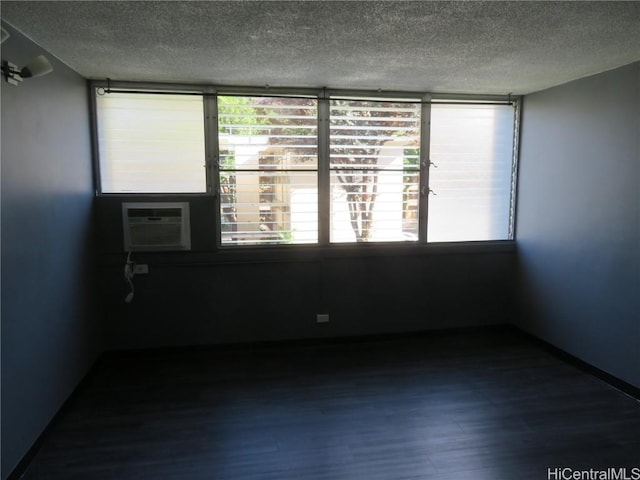 unfurnished room with wood-type flooring, a textured ceiling, and a wall unit AC