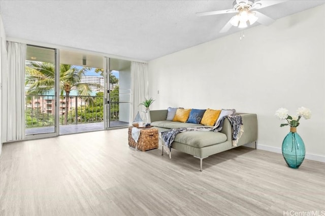 living room with ceiling fan, a healthy amount of sunlight, light hardwood / wood-style flooring, and expansive windows