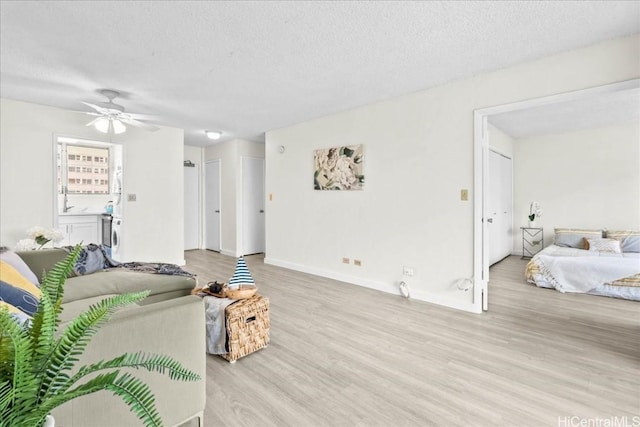 living room with a textured ceiling, ceiling fan, and light hardwood / wood-style floors