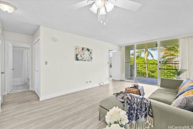 living room featuring ceiling fan, light wood-type flooring, a textured ceiling, and floor to ceiling windows