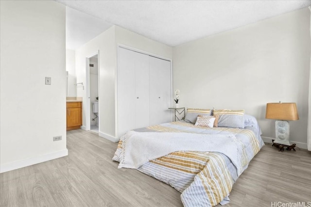 bedroom with light wood-type flooring, connected bathroom, and a closet