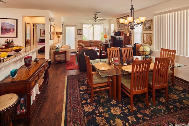 dining space featuring dark hardwood / wood-style flooring and ceiling fan with notable chandelier