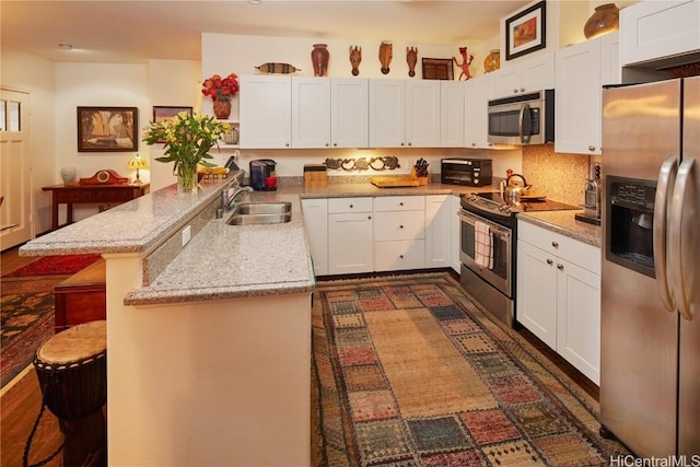 kitchen with white cabinetry, sink, stainless steel appliances, and a breakfast bar