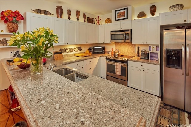 kitchen featuring sink, appliances with stainless steel finishes, white cabinetry, a kitchen breakfast bar, and kitchen peninsula