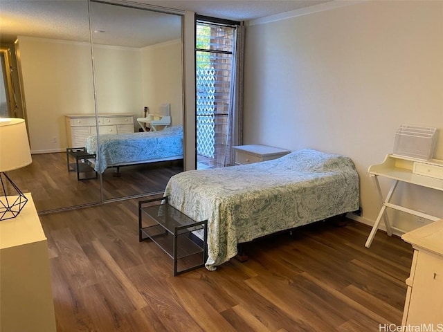 bedroom featuring ornamental molding, dark wood-type flooring, and a wall of windows