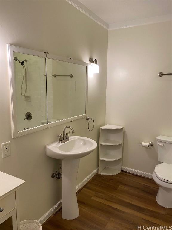 bathroom featuring sink, crown molding, hardwood / wood-style floors, a shower, and toilet