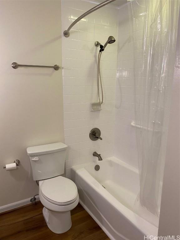 bathroom featuring hardwood / wood-style flooring, shower / tub combo with curtain, and toilet