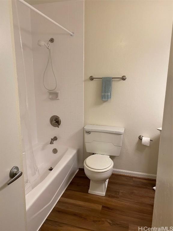 bathroom with hardwood / wood-style floors, shower / bath combination with curtain, and toilet