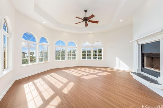 unfurnished sunroom with ceiling fan and a raised ceiling