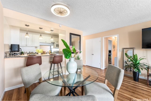 dining room with wood-type flooring and a textured ceiling