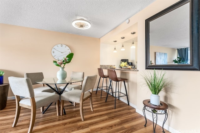 dining area with wood-type flooring and a textured ceiling