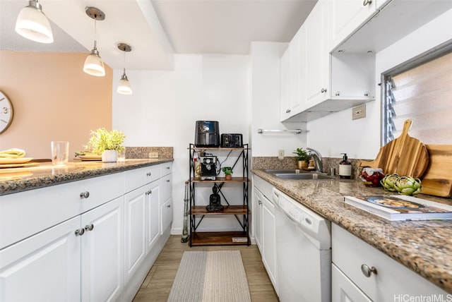 kitchen featuring pendant lighting, white dishwasher, white cabinets, sink, and light stone countertops