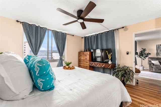 bedroom featuring ceiling fan, hardwood / wood-style floors, and a textured ceiling