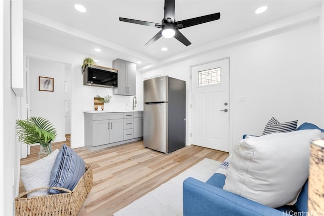 living room with light hardwood / wood-style floors, ceiling fan, and sink