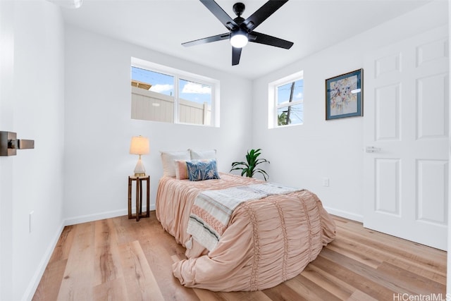 bedroom with ceiling fan, light hardwood / wood-style flooring, and multiple windows