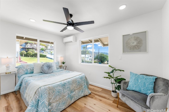 bedroom with a wall unit AC, ceiling fan, and hardwood / wood-style flooring