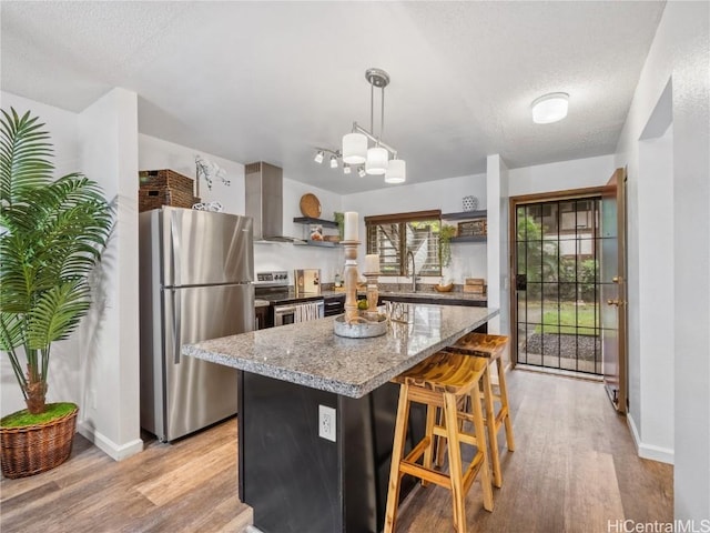 kitchen featuring light hardwood / wood-style flooring, decorative light fixtures, a kitchen bar, a kitchen island, and appliances with stainless steel finishes