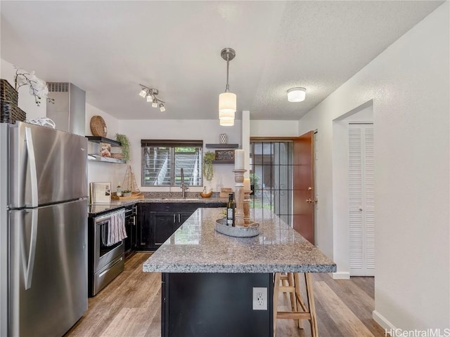 kitchen featuring light stone countertops, a center island, hanging light fixtures, stainless steel appliances, and a breakfast bar