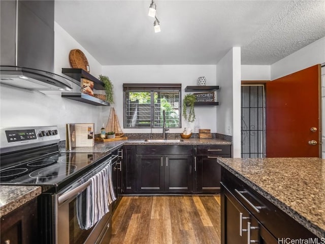 kitchen with wall chimney range hood, sink, electric range, dark hardwood / wood-style floors, and dark stone countertops