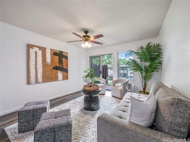 living room with a textured ceiling, ceiling fan, and dark wood-type flooring