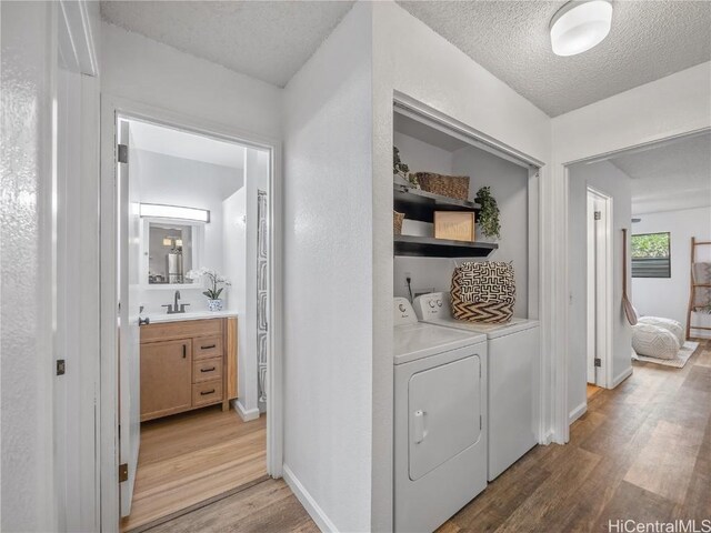 laundry area with separate washer and dryer, light hardwood / wood-style flooring, and a textured ceiling