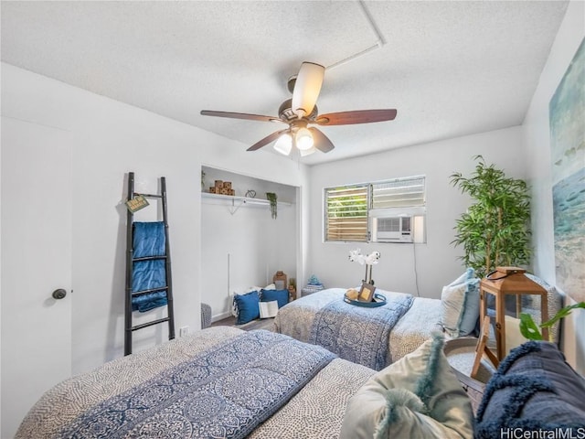 bedroom with ceiling fan, cooling unit, a textured ceiling, and a closet