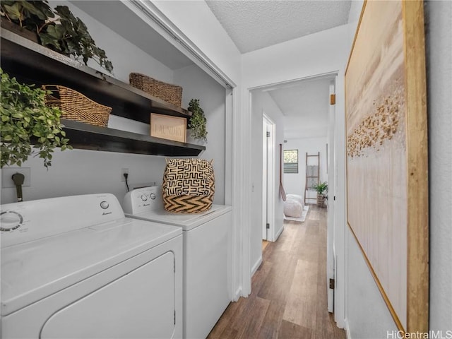 laundry area with washer and clothes dryer, a textured ceiling, and light hardwood / wood-style flooring