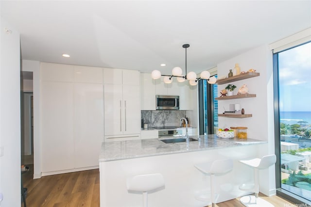 987 Queen St Unit 1401, Honolulu, HI 96814 - kitchen with stainless steel microwave, backsplash, a peninsula, white cabinetry, and open shelves