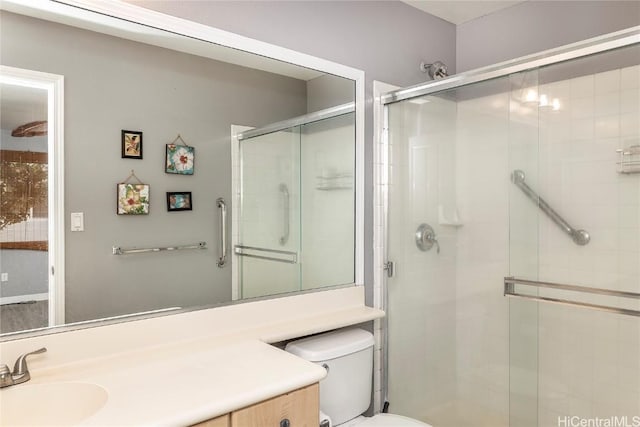 bathroom with vanity, a shower with shower door, and toilet