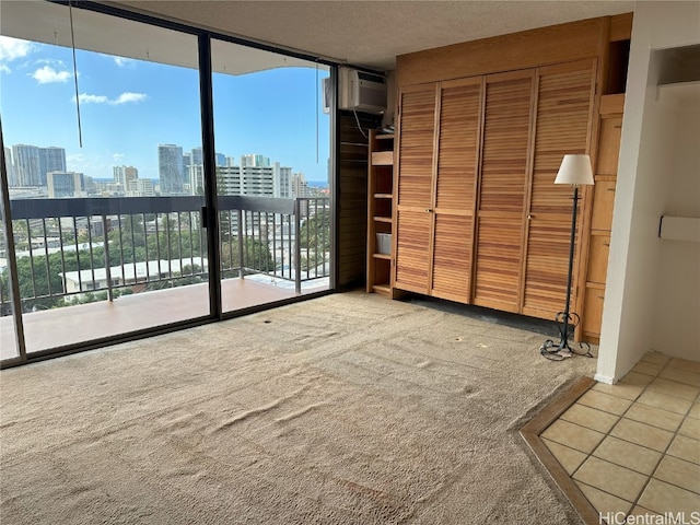 unfurnished bedroom with carpet flooring, a wall mounted air conditioner, a wall of windows, access to outside, and a closet