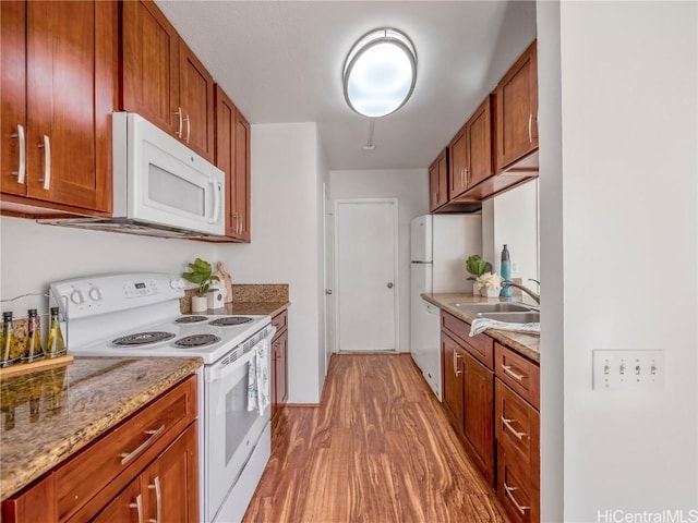 kitchen featuring light stone counters, white appliances, sink, and light hardwood / wood-style flooring